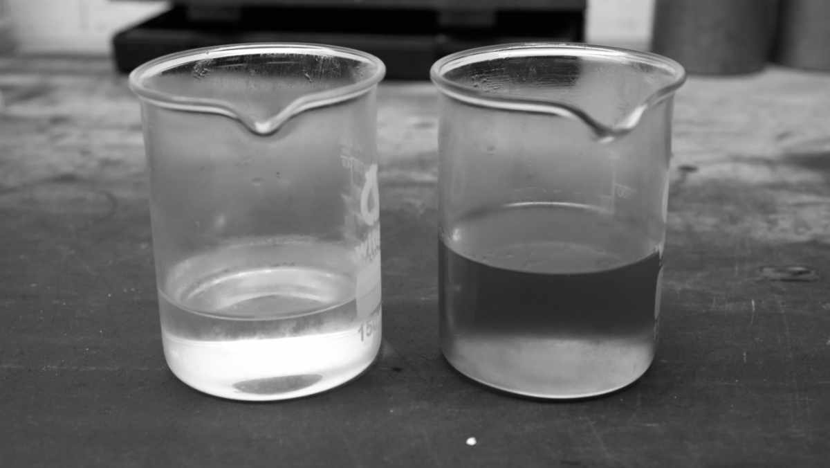 alte_und_neue_bremsfluessigkeit Neue und verbrauchte Bremsflüssigkeit in einem Becherglas